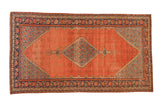 Antique Persian Malayer carpet with a blue stepped diamond medallion on a faded madder red field with geometric spandrels.