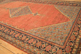 Angled view of an antique Malayer carpet showing the detailed corner spandrel and pomegranate border.