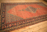 Angled perspective of an antique Malayer showing the stepped diamond medallion on its madder red field.