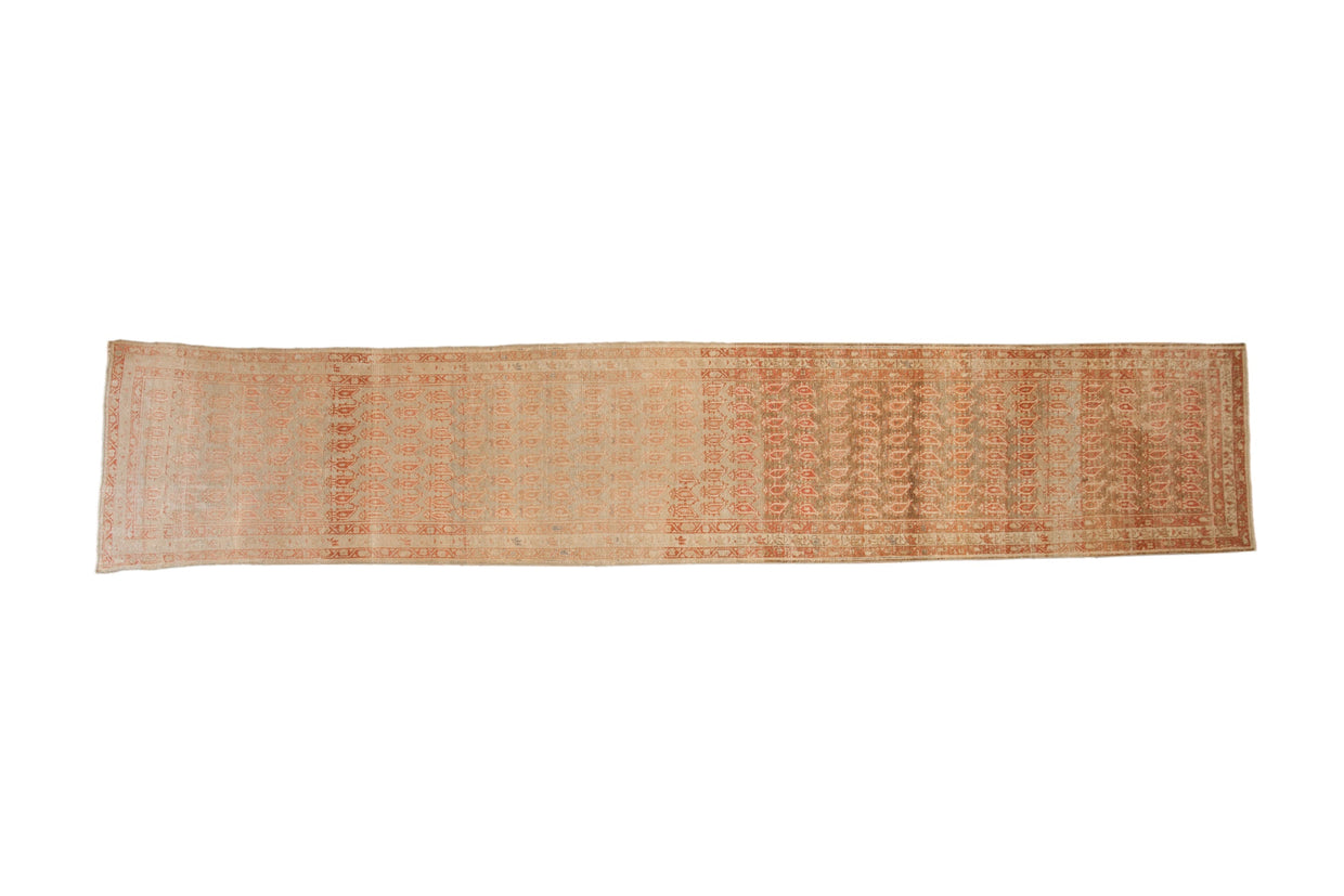 Distressed antique Malayer runner featuring an allover boteh pattern in pomegranate red on an antique ivory background.