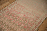 Angled view showing the distressed, low-pile texture and shifting field color on this antique runner.