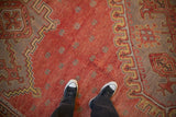 Vintage Oushak carpet texture showing mostly even wear across the red, hand-knotted pile.