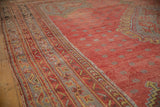 Angled view of a vintage Oushak carpet's geometric border and mostly even low-pile texture.