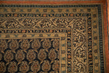 Antique Tabriz carpet corner showing navy blue scrolled vine and pawn borders on antique ivory.