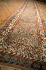 Long perspective view of an antique Serab runner showing its repeating geometric medallions and camel hair pile.