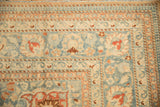 Corner of a vintage Tabriz rug showing pawn and meandering vine borders in blue and ivory.