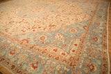 Angled view of a distressed Tabriz corner with a serrated sky blue spandrel and rust-colored florals.