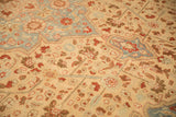 Detail of the distressed, low pile showing floral motifs in rust, ivory, and powder blue tones.