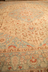 Low angle view across the distressed pile of a Tabriz rug, showing even wear and faded floral motifs.