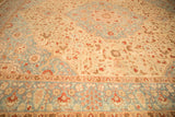 Angled perspective across the distressed floral field of a vintage Tabriz rug, highlighting its low-pile texture.
