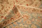 The folded corner of a vintage Tabriz carpet reveals its hand-knotted texture and secured side selvage.