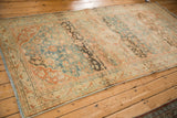 Angled view of a distressed Mahal rug showing time-softened charcoal abrashes across a teal field.