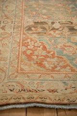 Angled detail of a vintage Mahal rug's worn corner, showing terracotta and dusty teal floral motifs.