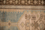Close-up of the worn, hand-knotted pile showing the coffee brown border and sky blue details.
