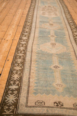 Angled view of a distressed Caucasian runner highlighting the coffee brown geometric border and low pile.