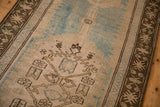 Angled view of the distressed Caucasian runner's low pile, coffee brown border, and sky blue motifs.