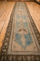 Low angle view down the length of a distressed vintage Caucasian runner, showing its soft, worn texture.