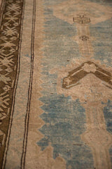 Angled detail of the distressed rug's low pile texture, showing the geometric border and worn field.