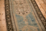 Angled view of the distressed Caucasian runner's coffee brown border and sky blue field.
