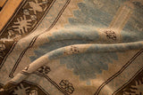 Soft folds of a vintage Caucasian runner showing the textured low pile and geometric border.