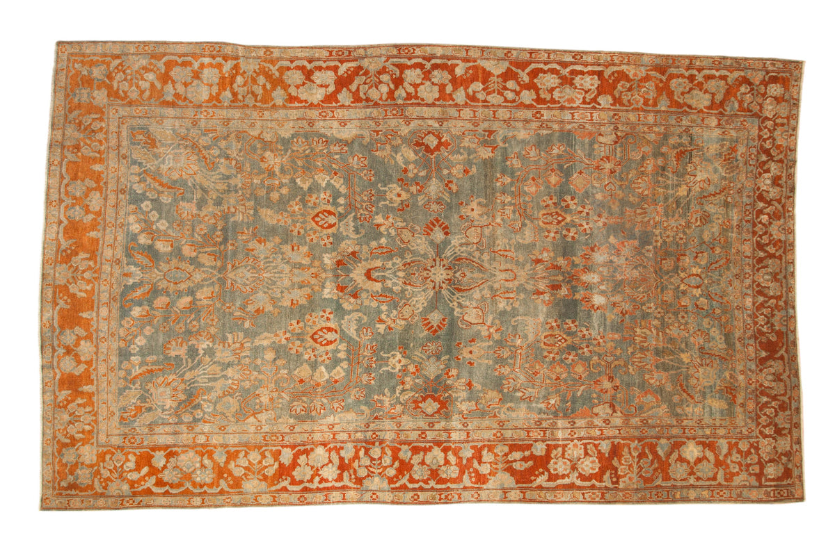 Antique distressed Sarouk carpet with allover floral sprays on a dusty blue field and a rich terracotta border.