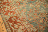 Angled view of an antique Sarouk's terra cotta border and dusty blue field with floral sprays.