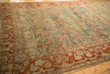 A rich terra cotta floral border contrasts with the dusty blue field of an antique distressed Sarouk carpet.