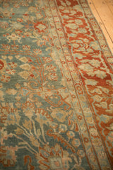 Short pile texture of a distressed Sarouk carpet with dusty blue floral sprays and a deep terra cotta border.