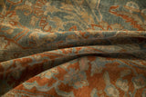 Soft folds of an antique Sarouk carpet showing the low pile texture in dusty blue and terra cotta.