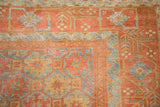 Geometric blossom and scrolled vine borders on a vintage Belouch rug in madder red and powder blue.