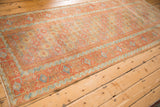 Angled view of the vintage Belouch runner showing its geometric floral guls in faded madder root red and ochre.