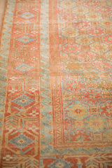 A distressed vintage Belouch runner's low pile, showing geometric floral guls beside a ribboned wave border.