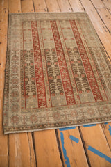 Angled view of the abrashed ground and striped agricultural panels of a distressed Bijar rug.