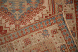 Corner of a vintage Serab rug folded to show its hand-knotted back and low-pile texture.