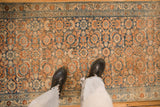 A casual, overhead view of a distressed Persian runner's denim blue and rust Herati design.
