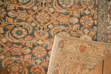 A corner of the vintage Malayer rug is turned back, revealing the rug's hand-knotted foundation.