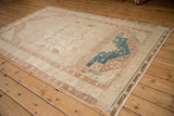Perspective view of a distressed Hamadan rug contrasting its ivory field with a dusty sapphire blue medallion.