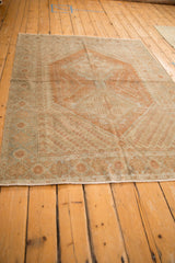 Angled view of a distressed vintage Afshar rug, showcasing its time-softened copper medallion and dusty blue border.