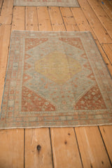 Angled view of a distressed Persian rug's worn texture and powder blue and terra cotta palette.