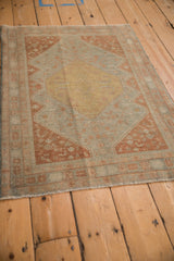 Angled perspective of a distressed Persian rug with a dusty gold medallion and powder blue field.