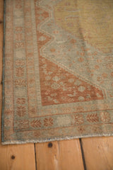 Corner detail of a distressed Persian rug showing a terra cotta rust spandrel and floral border.