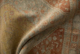 Softly folded Persian rug showing the distressed, low-pile texture and hand-knotted weave.