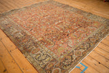 Angled view of a vintage Mehrivan carpet, highlighting the distressed texture of its rust and teal pattern.