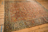 Angled view of a distressed Mehrivan rug, highlighting its rust-red geometric field and complex borders.