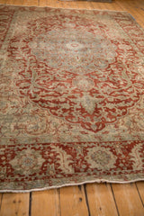 Perspective view across a distressed Ahar carpet, highlighting decorative wear on its ruby red arabesques.