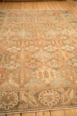 Angled view across the distressed Bakhtiari rug's surface, showing the low pile and panelled motifs.