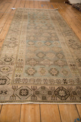 Angled view down a distressed Hamadan runner showing its repeating geometric design in dusty blue and beige.