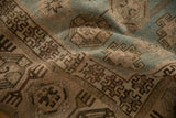 Hand-knotted texture and geometric motifs in dusty blue and brown on a distressed vintage rug.