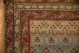 Vintage Karabagh runner corner showing the raspberry vine border and textured dusty teal field.