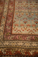 Close-up detail of a vintage Karabagh rug's raspberry vine border and dusty teal blue field.
